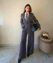 Modella indossa giacca Claure Mode grigia foderata con spalline imbottite e pantaloni a gamba larga stile ufficio