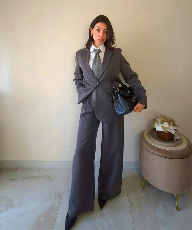 Modella indossa giacca Claure Mode grigia foderata con spalline imbottite e pantaloni a gamba larga stile ufficio