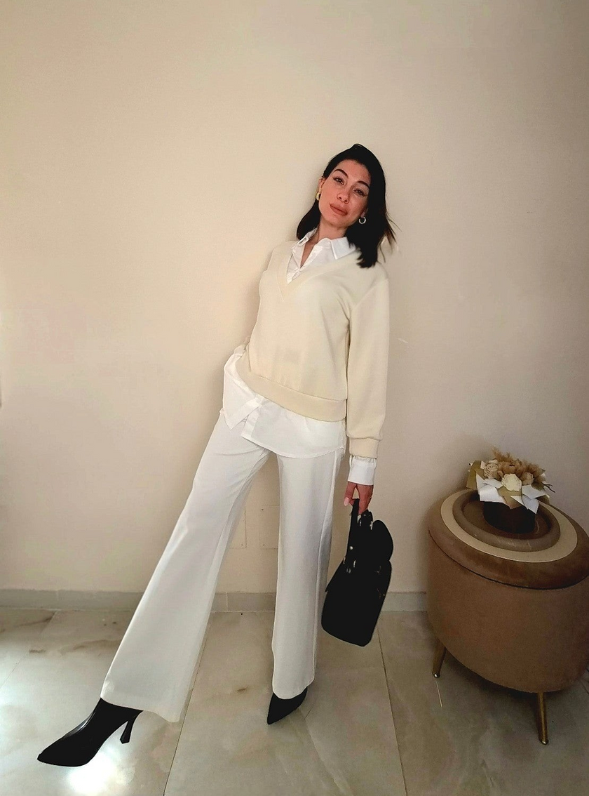 Modella indossa pantaloni Claure Mode Paige bianchi elasticizzati a gamba larga con camicia e maglione